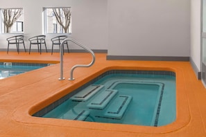 An indoor swimming pool with a clear water path, orange poolside, and chairs. - Hampton Inn Olathe (Olathe)