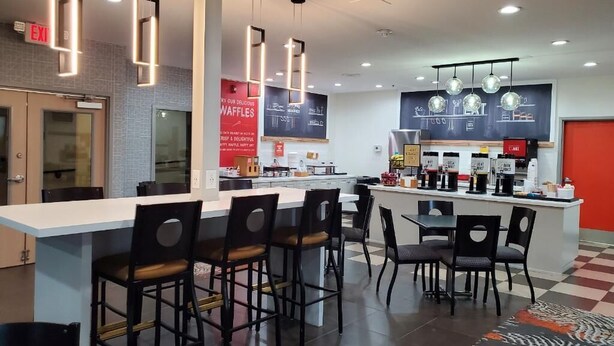 Un área de cocina moderna con una isla central, taburetes de bar e iluminación colgante.