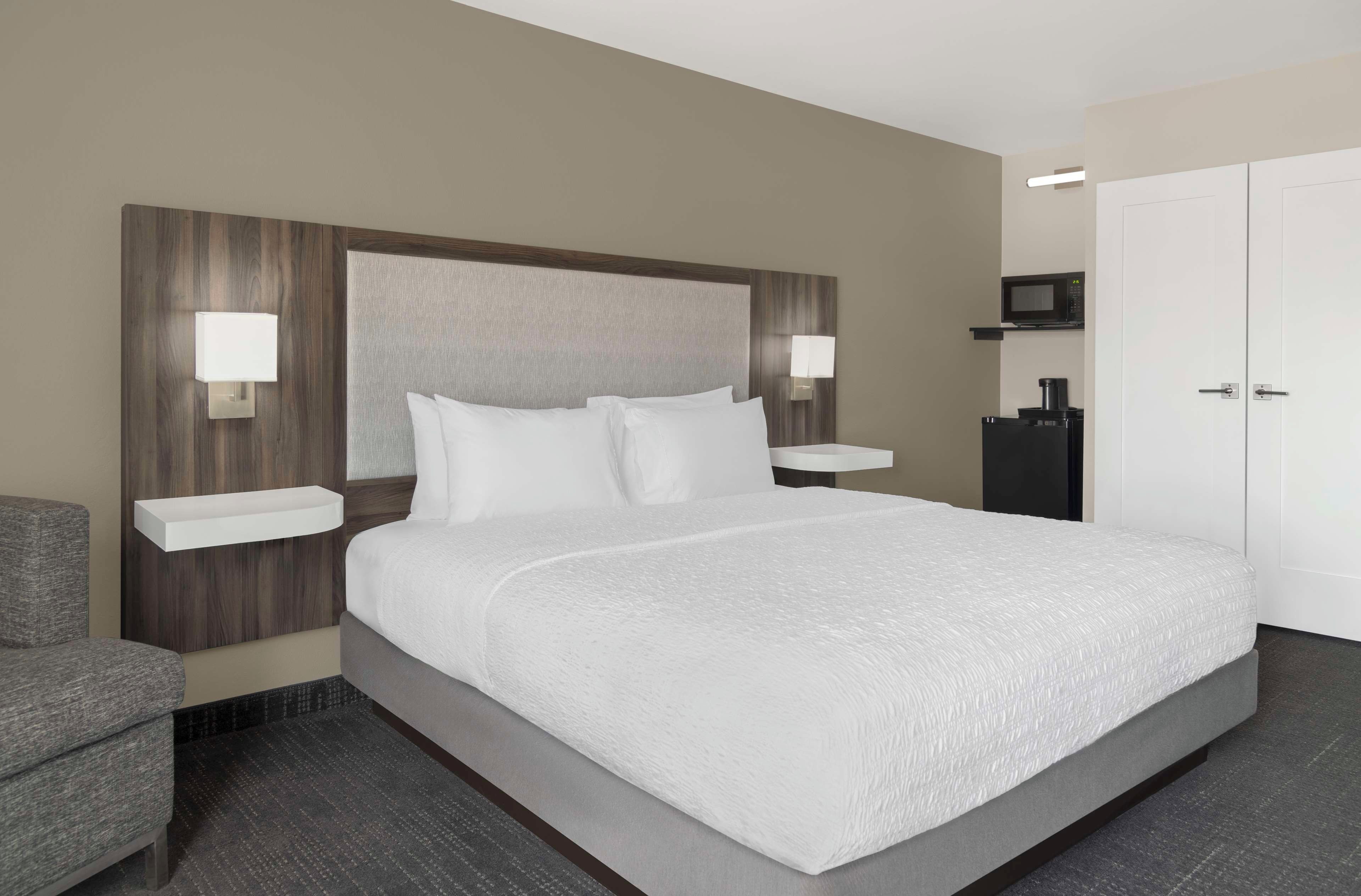 A hotel room with a large bed, two bedside tables with lamps, a wardrobe, and a microwave.