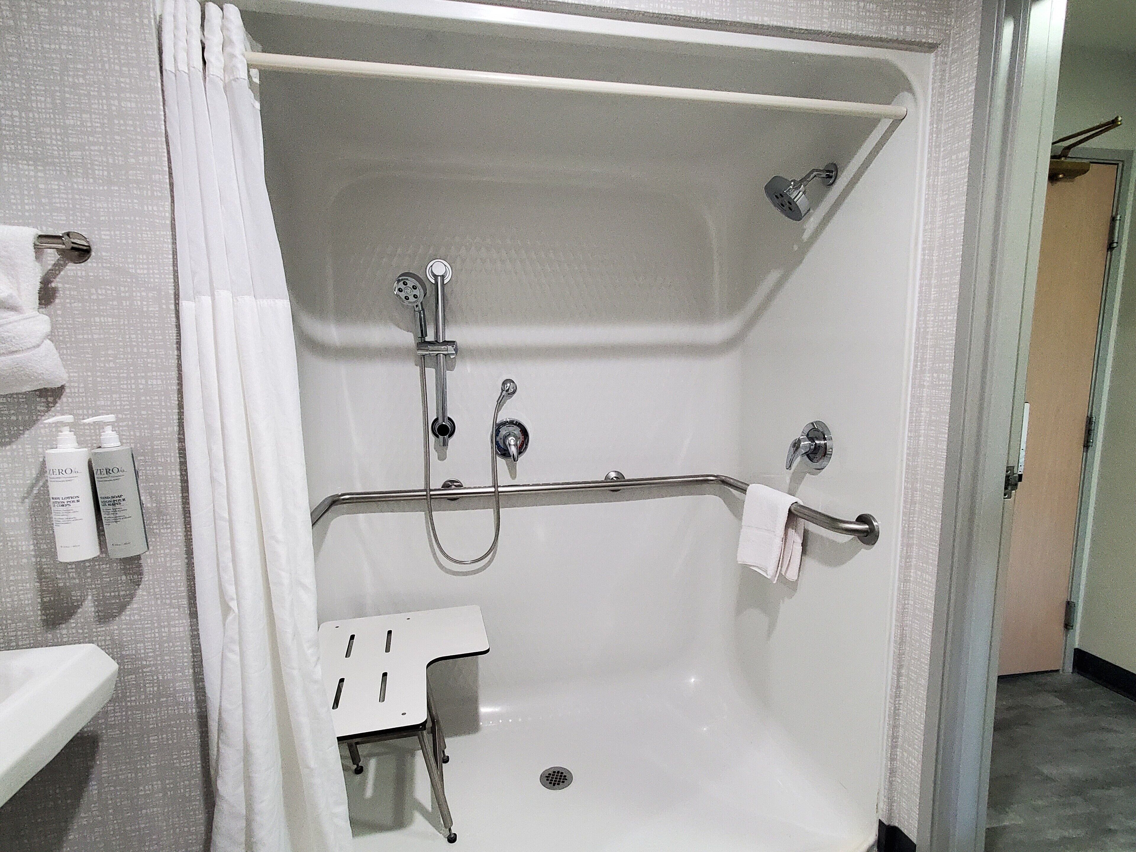 Ducha a nivel con barra de apoyo, cabezal de ducha manual y grifo de mano.