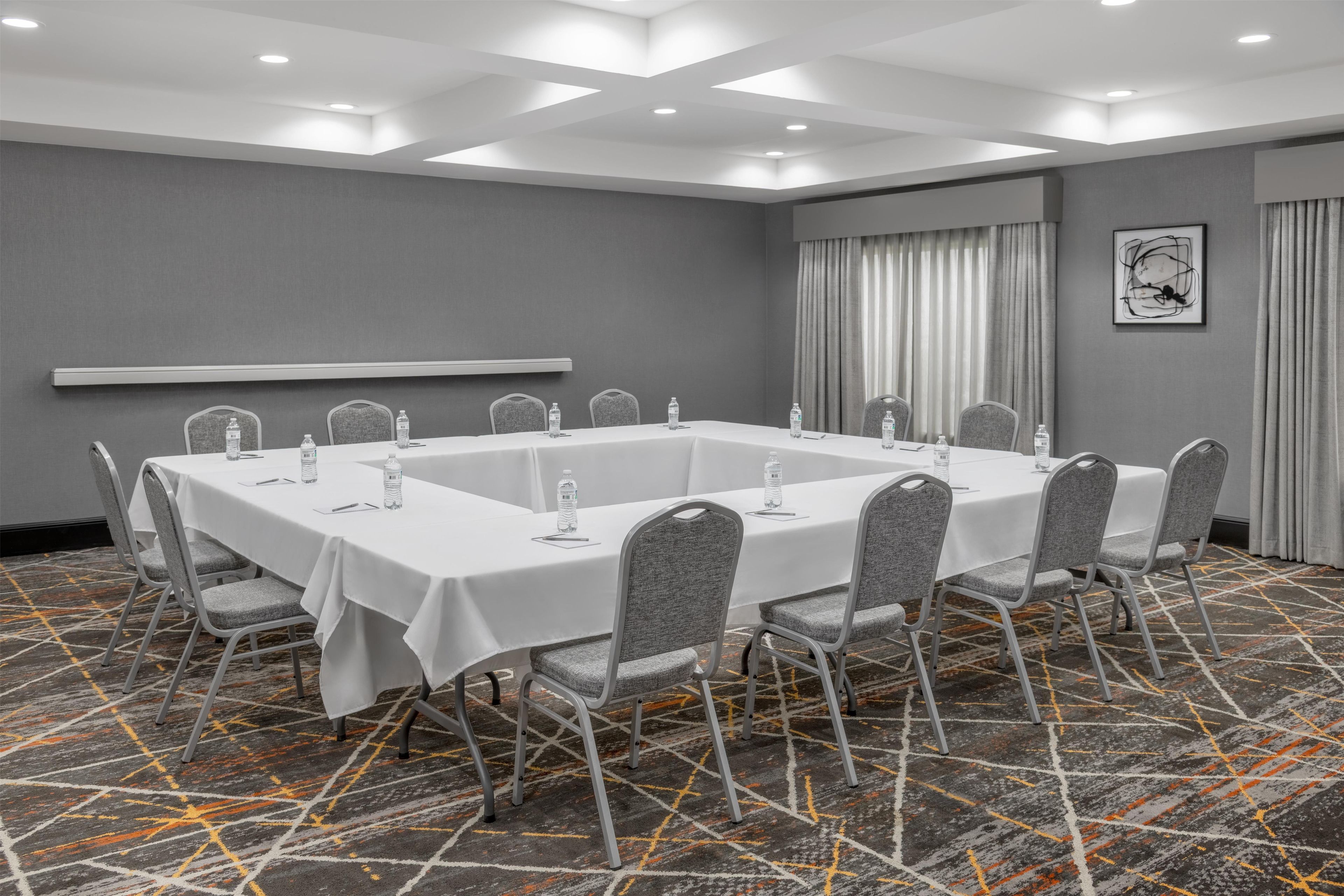 A conference room with a long table, chairs, and a projector screen.