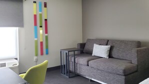 Una sala moderna con un sofá gris, una mesita auxiliar y un sillón amarillo.