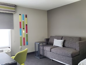 A modern living room with a grey sofa, a small side table, and a yellow chair. - Hampton Inn Olathe (Olathe)
