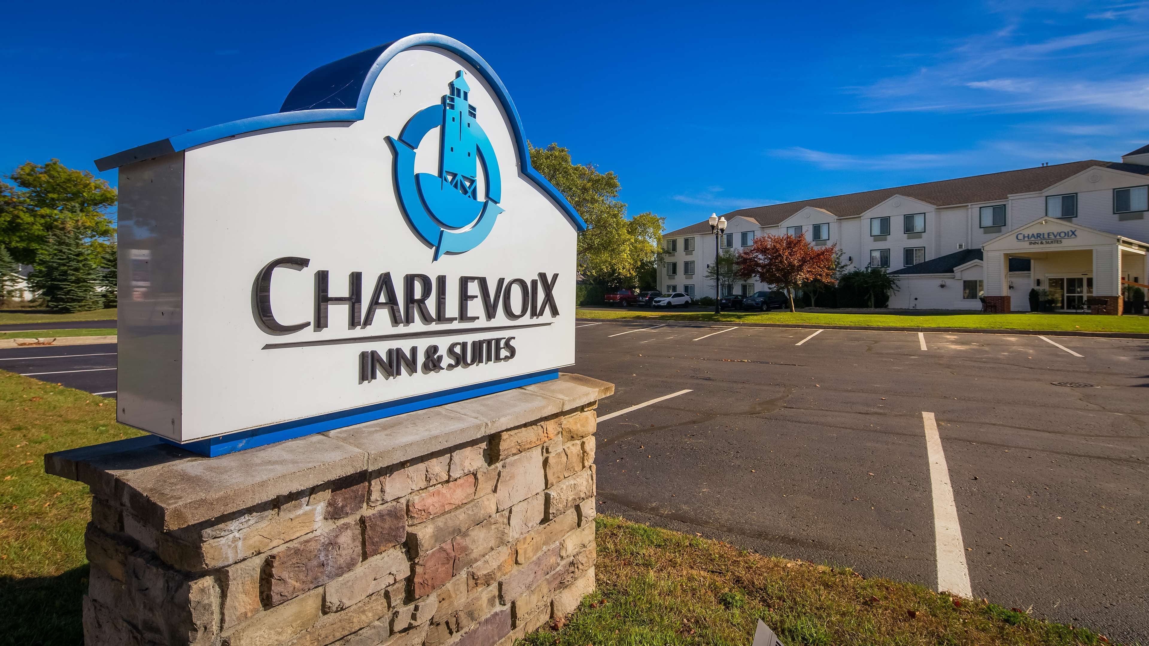 A sign for Charlevoix Inn & Suites with a clear view of the building in the background.