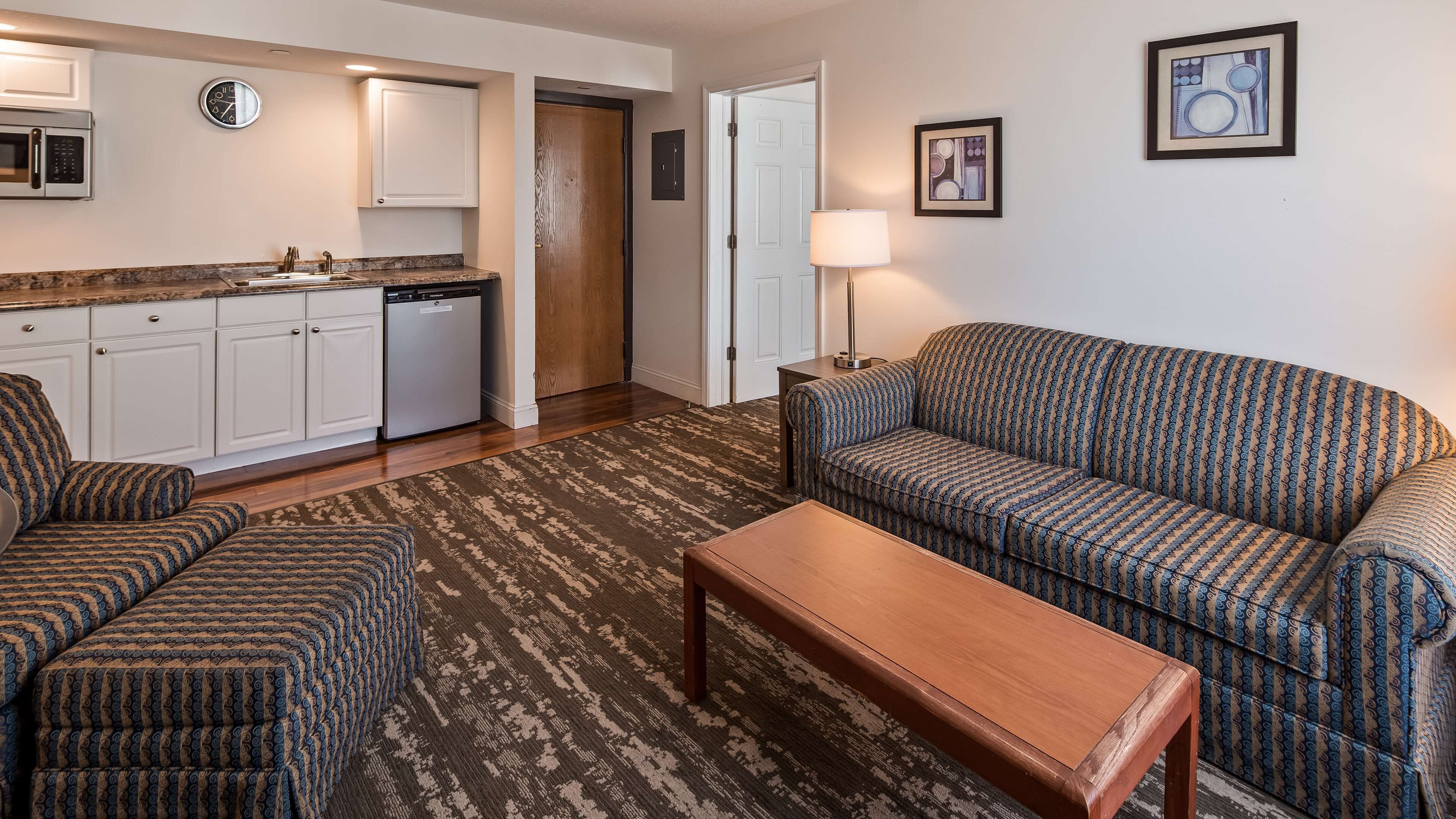 A compact living space with a kitchenette, a sofa, a coffee table, and a patterned rug.
