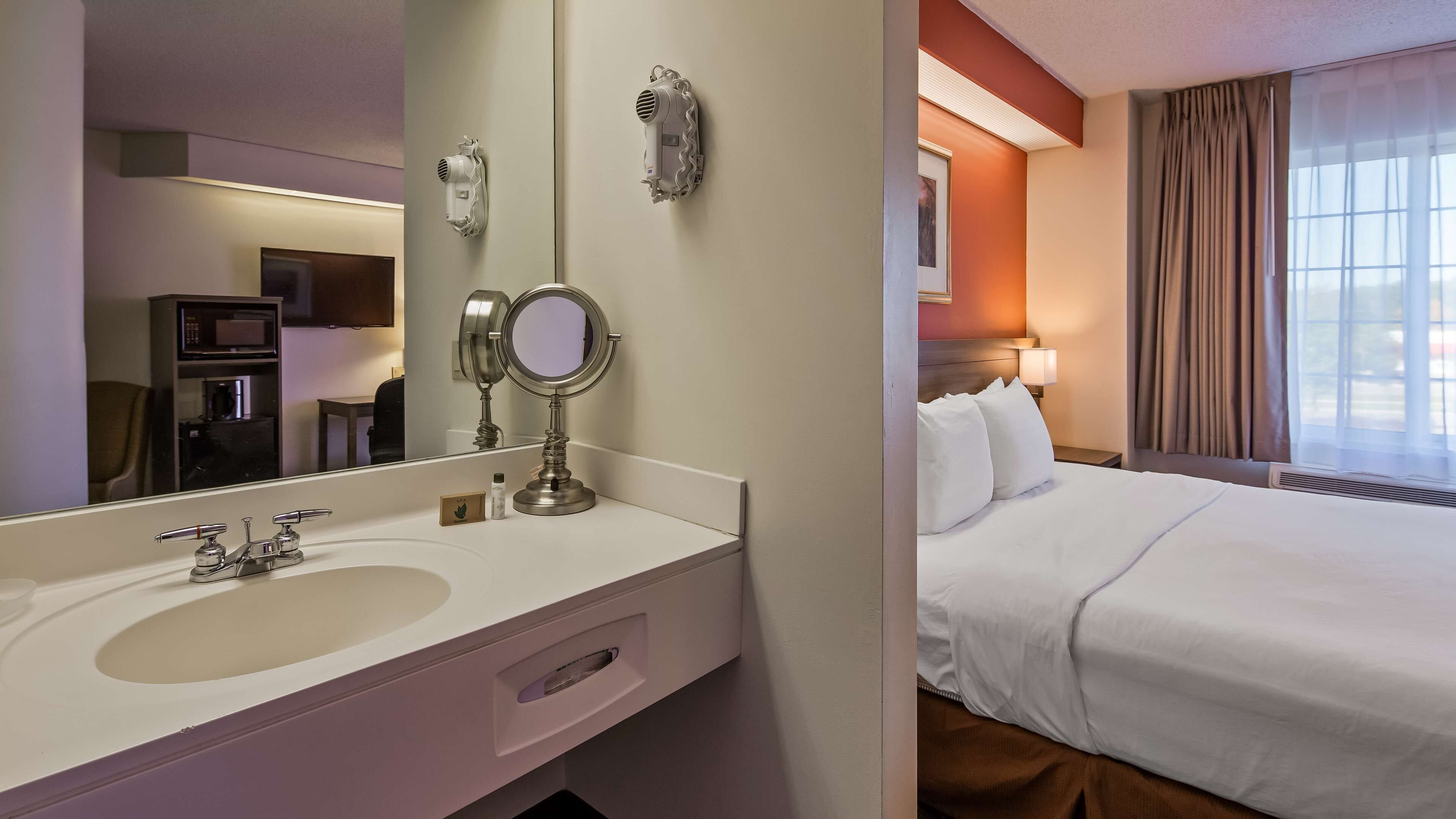 Habitación de hotel con tocador, cama y ventana con cortinas.