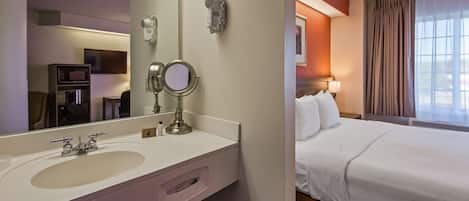 Habitación de hotel con tocador, cama y ventana con cortinas.