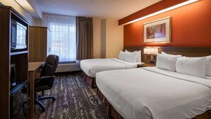 A hotel room with two beds, a desk, a chair, and a large window with curtains. - Charlevoix Inn & Suites SureStay Collection by Best Western (Charlevoix)