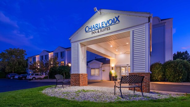 A Charlevoix Inn & Suites with a covered entrance, outdoor seating, and a gravel area. - Charlevoix Inn & Suites SureStay Collection by Best Western (Charlevoix)