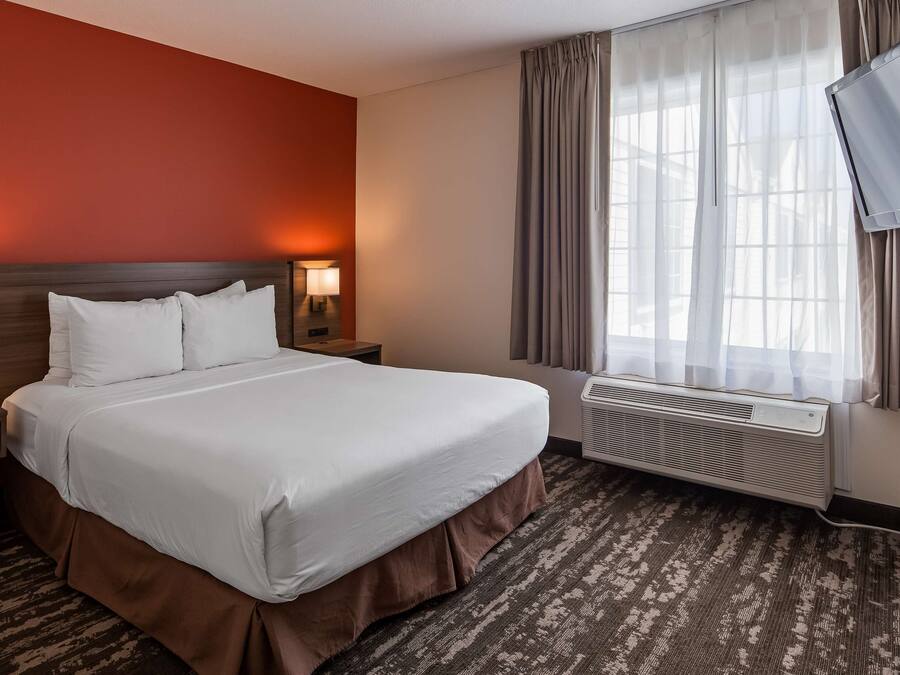 Une chambre d’hôtel avec un grand lit, deux lampes de chevet, un téléviseur à écran plat et une fenêtre avec des rideaux.