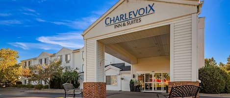 Het uiterlijk van Charlevoix Inn & Suites, met een overdekte ingang, twee banken en een grindpad.