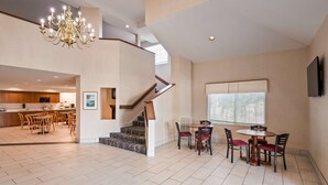A spacious living area with a staircase, dining table, and chairs. - Charlevoix Inn & Suites SureStay Collection by Best Western (Charlevoix)