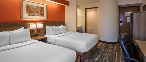 A hotel room with two beds, a desk, a chair, and a painting on the wall.