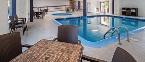 An indoor swimming pool with a lounge area, chairs, and a staircase leading to an upper level.