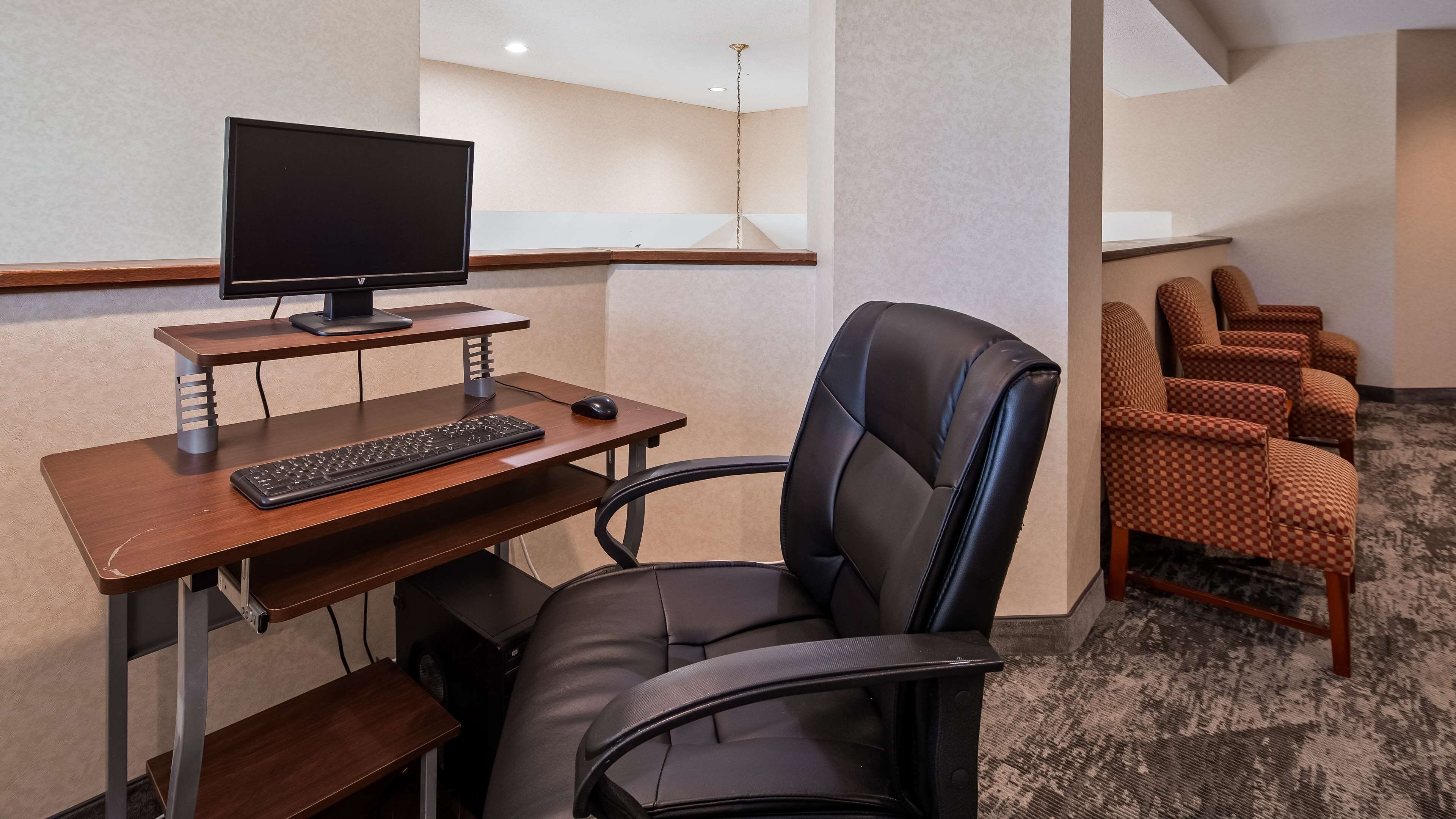 Ein Hotelzimmer mit Schreibtisch, Computer und Stuhl. Ein Fernseher ist über dem Schreibtisch an der Wand befestigt.