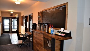 A coffee shop with a wooden counter, a chalkboard menu, and a seating area with chairs. - Americas Best Value Inn Marquette (Marquette)