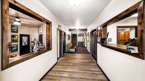 A hallway with wooden flooring, framed mirrors, and a reception desk. - Americas Best Value Inn Marquette (Marquette)
