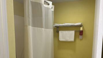 Un baño con inodoro blanco, cortina de ducha y toallero con una toalla blanca.