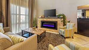 Una sala de estar con chimenea, sofá, sillón y un televisor de pantalla plana.