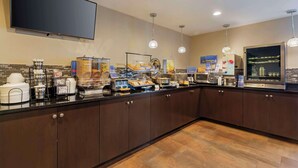 Una barra de desayuno con televisión de pantalla plana, máquinas de café y diversas opciones de alimentos.