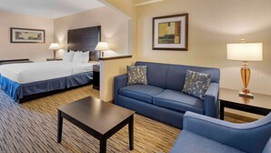 Una habitación de hotel con cama, sofá, una mesa de centro y dos lámparas.