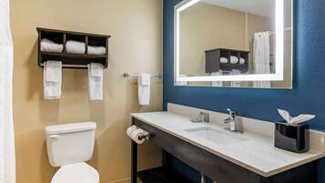 A bathroom with a toilet, a sink with a mirror, and a towel rack with folded towels.