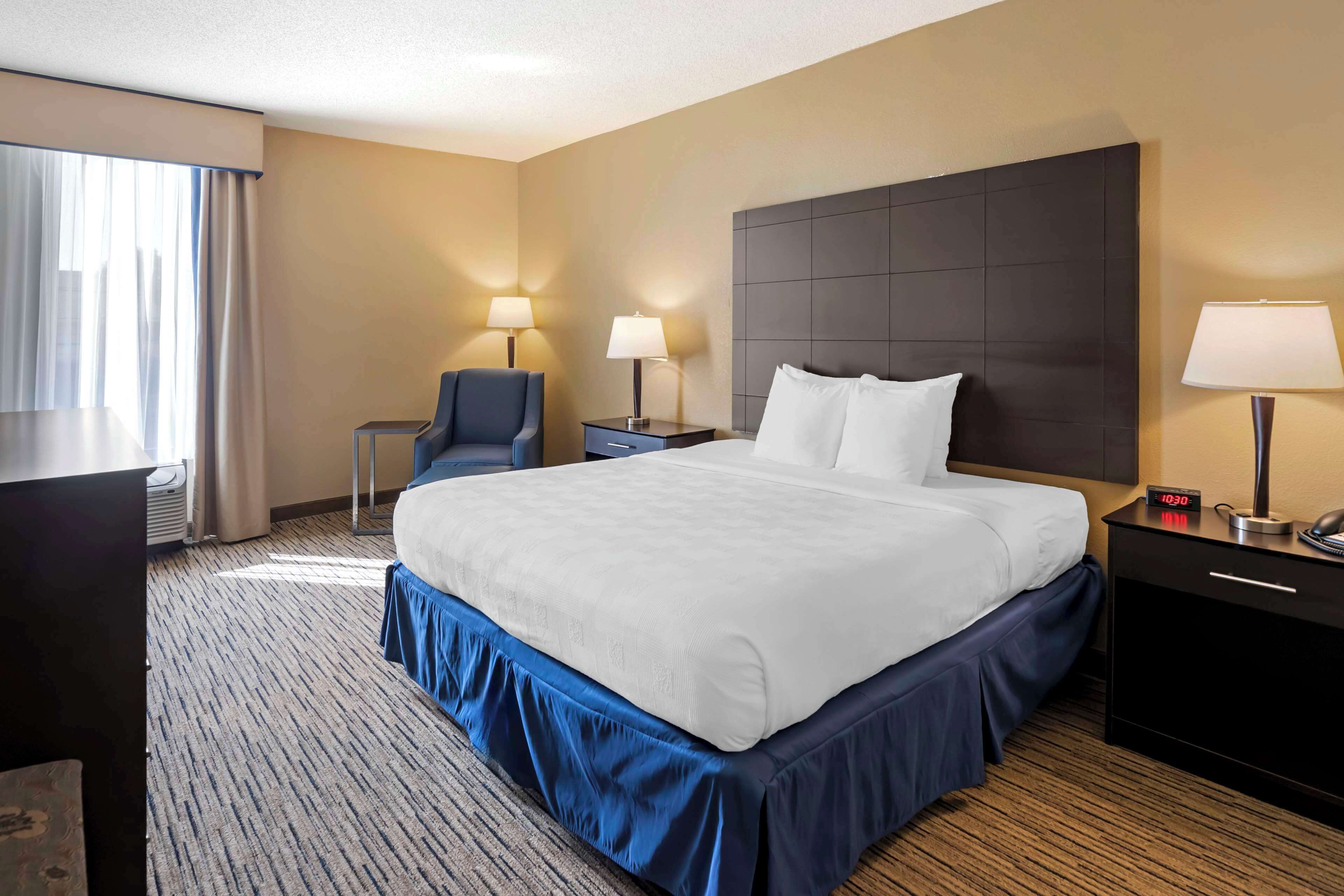 A hotel room with a large bed, two bedside tables with lamps, a desk, and a chair.