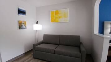 Una sala de estar moderna con un sofá gris, una lámpara de pie y arte abstracto en la pared.