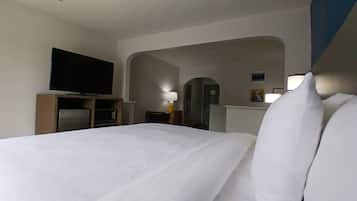 A hotel room with a bed, a television, a microwave, and a desk with a lamp.