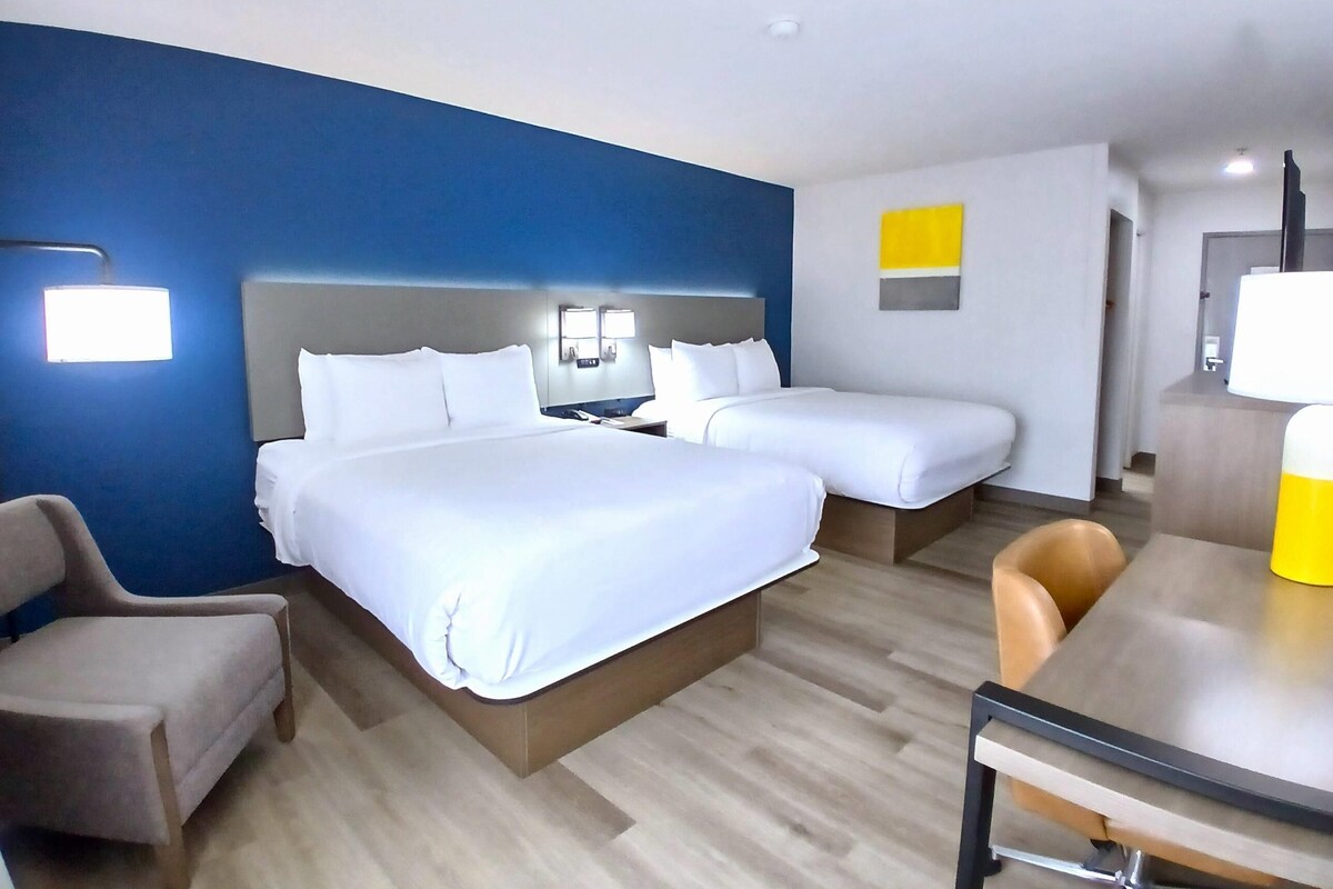 Ett hotellrum med två sängar, ett skrivbord, en stol och ett badrum.
