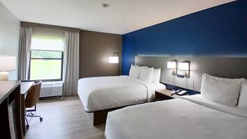 A hotel room with two beds, a desk, a chair, and a window with curtains.