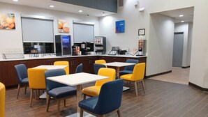 A modern restaurant with a counter, yellow and blue chairs, and a coffee machine. - Comfort Inn Marion near Downtown & Blue Ridge PKWY (Marion)