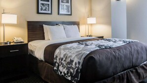 A hotel room with a large bed, two bedside tables with lamps, a phone on the left table, and two framed pictures on the wall above the bed. - Sleep Inn Florence North (Florence)
