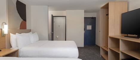 A hotel room with two beds, a TV, a desk, and a wardrobe.