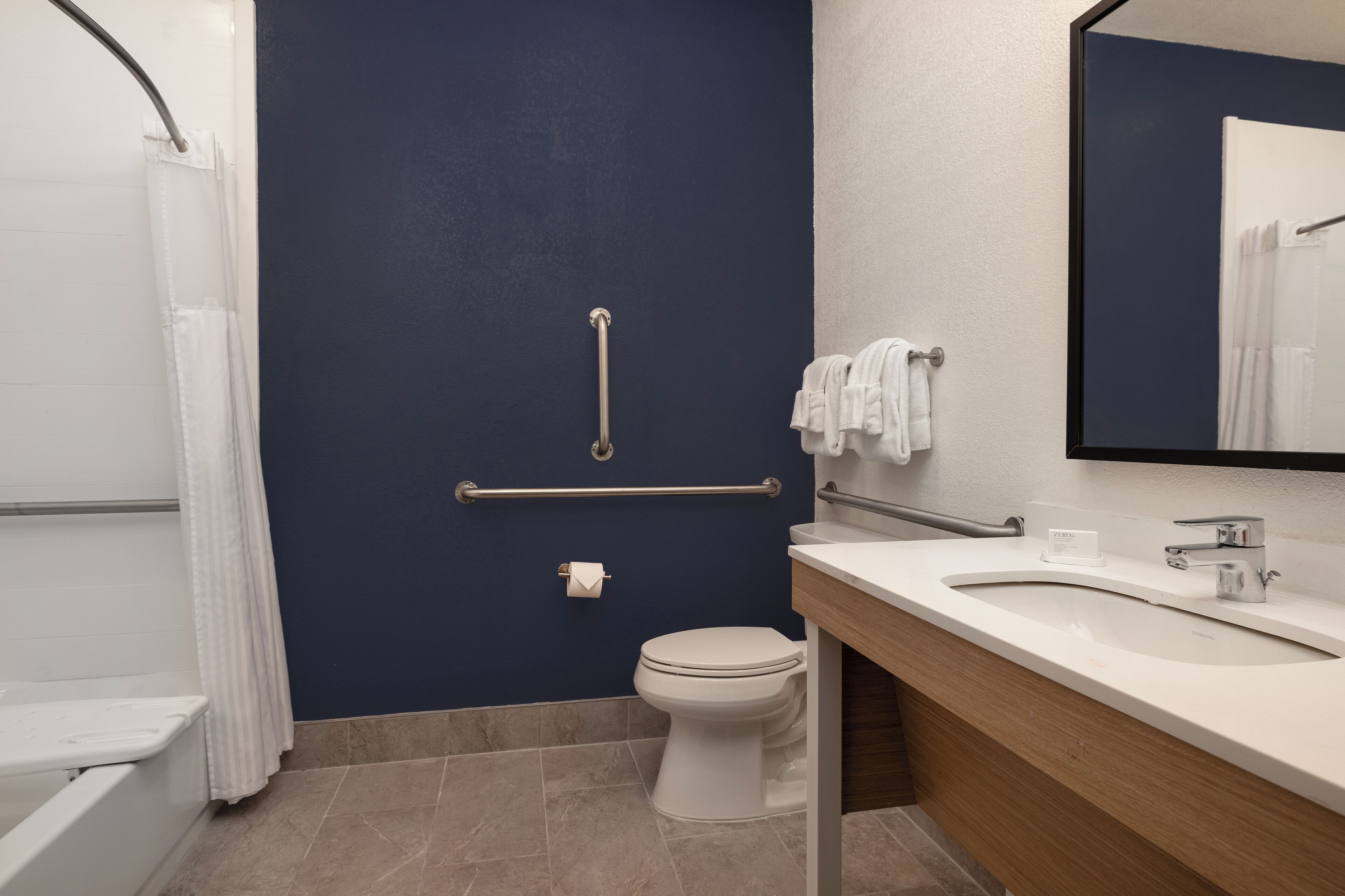 A bathroom with a white toilet, a sink with a mirror, and a shower curtain.