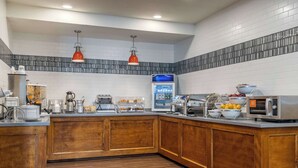 Una cocina moderna con armarios de madera, refrigerador empotrado, estación de café y microondas.