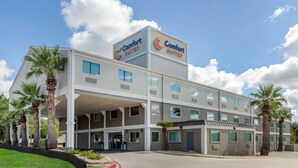 Un hotel Comfort Suites de diseño moderno, con varios pisos, amplias ventanas y una zona de entrada cubierta.