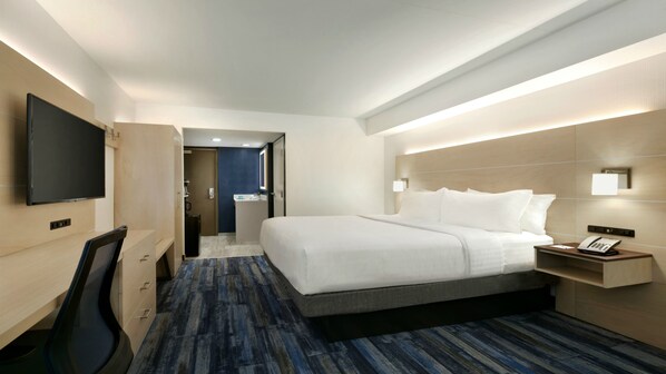 A hotel room with a large bed, a desk with a chair, a TV mounted on the wall, and a bedside table with a phone. - Holiday Inn Express Williamsbrg Busch Gardens Area by IHG (Williamsburg)