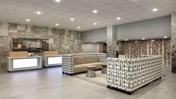 A hotel lobby with a reception desk, seating area, and a patterned wall.