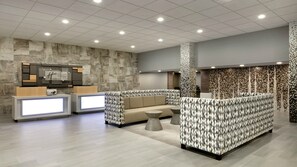 A hotel lobby with a reception desk, seating area, and a patterned wall. - Holiday Inn Express Williamsbrg Busch Gardens Area by IHG (Williamsburg)
