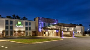 A Holiday Inn Express building with a modern design, featuring a prominent entrance and a parking lot. - Holiday Inn Express Williamsbrg Busch Gardens Area by IHG (Williamsburg)