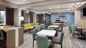 Eine moderne Hotelhalle mit Sitzgelegenheiten, einer Rezeption und einer Bar.