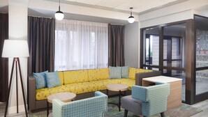 Ein modernes Wohnzimmer mit einem gelben Sofa, zwei runden Tischen und gemusterten Stühlen.