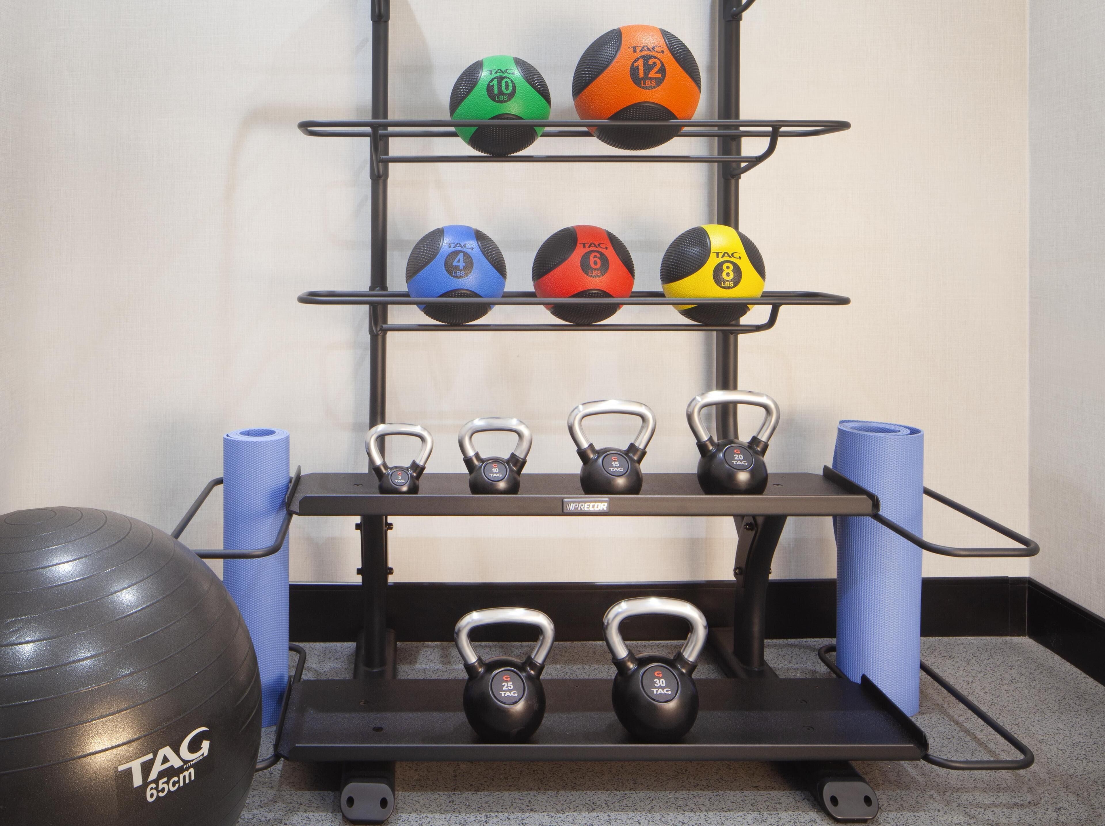 A home gym setup with kettlebells, exercise balls, and yoga mats.