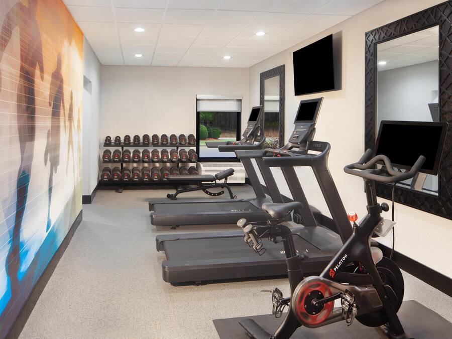 Een sportschool met loopbanden, een elliptische trainer en een hometrainer.