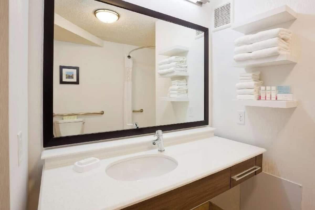 A bathroom with a white sink, a large mirror, and a towel rack.
