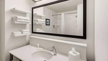 Un baño moderno con un espejo grande, lavamanos blanco, toalleros y cortina de ducha.