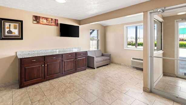 A modern kitchen with dark wood cabinets, a granite countertop, and a flat-screen TV mounted on the wall. - Rodeway Inn Oxford (Oxford)