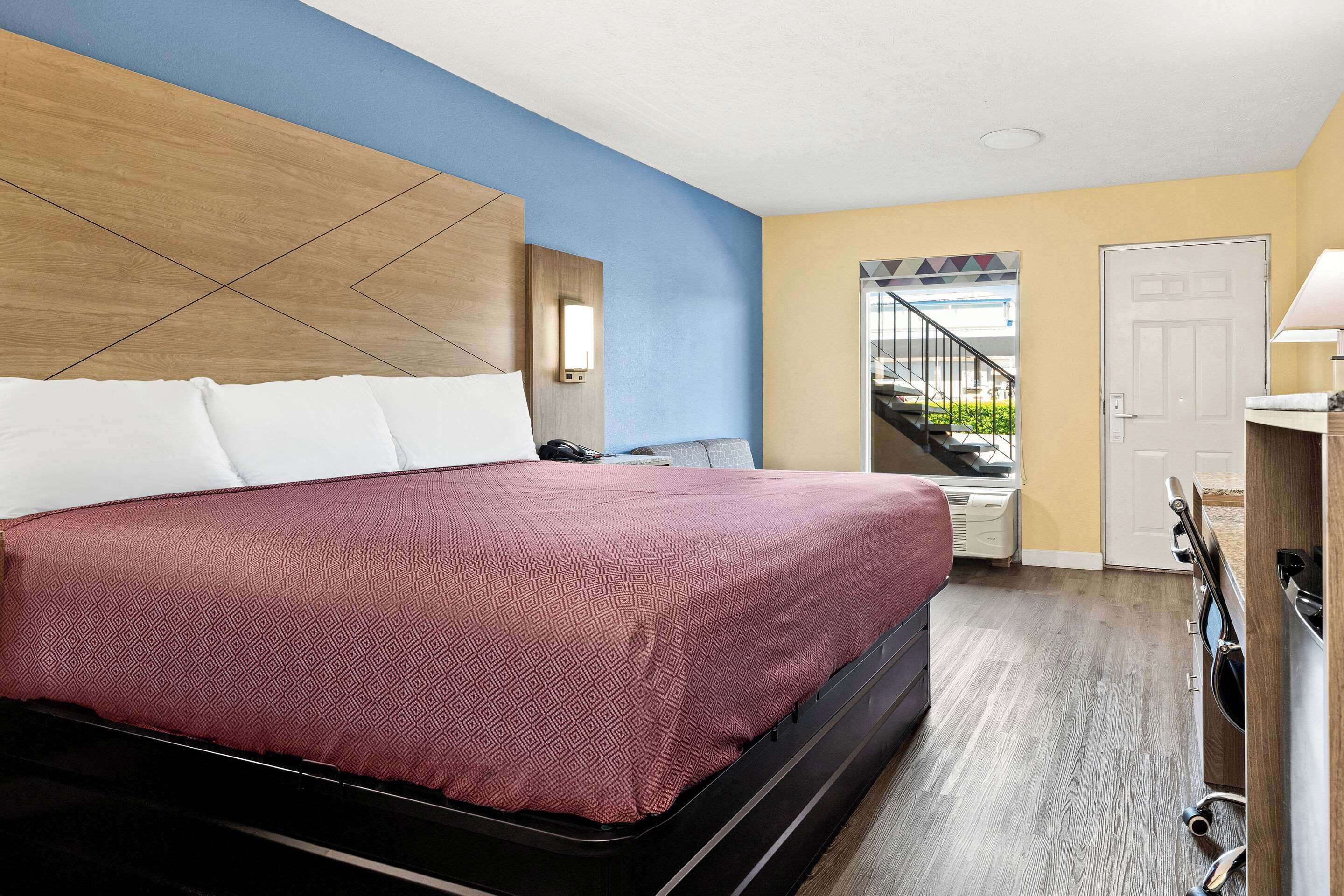 A hotel room with a bed, a desk, and a view of the outside.