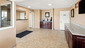A spacious kitchen with a granite countertop, wooden cabinets, and a tiled floor. - Rodeway Inn Oxford (Oxford)